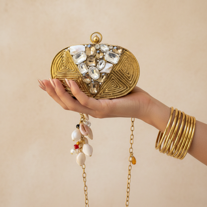 Siyana Mini Clutch - luxury editorial with gold bangles, hand holding clutch against limewash background